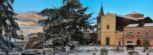 a building with a clock tower and a church with snow at La casa di Antonella in Nicolosi