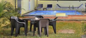 a table and chairs in front of a swimming pool at Sonikas Holiday Homes (Studio) in Candolim