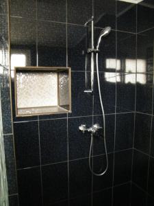 e bagno con piastrelle nere e doccia. di Iarca Cottage a Bucarest