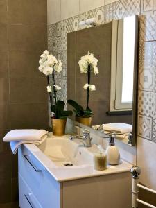 a bathroom with a sink and a mirror and flowers at Fra il Verde e l'Azzurro in Oristano