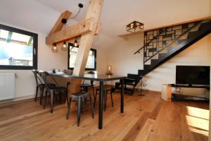 a dining room with a table and chairs and a staircase at Le Grenier du 11 in Gérardmer
