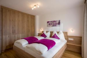 a bedroom with a large bed with purple and white pillows at Ferienwohnungen Obinghof in Söll