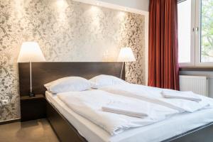 ein Schlafzimmer mit einem Bett mit zwei weißen Handtüchern darauf in der Unterkunft Waldhof Residenz in Offenbach