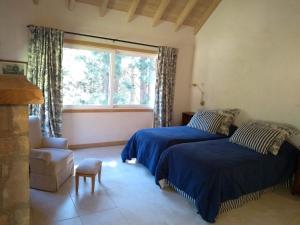 two beds in a room with a window and a chair at Villa Gutierrez Braun in San Martín de los Andes