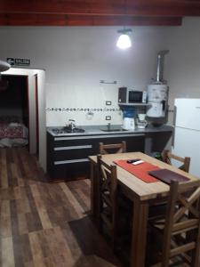 a kitchen with a table and a stove and a refrigerator at Departamento Teodelina in Quehué