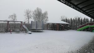 a playground covered in snow with a slide and a pavilion at Apartman Taktik in Veľký Meder