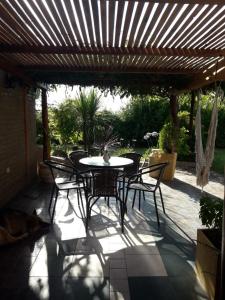 a patio with a table and chairs under a wooden pergola at Talita Cumi in Villa Santa Cruz del Lago