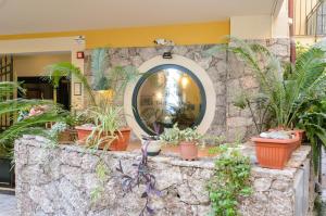 a stone wall with potted plants in front of a building at Le Tartarughe Aparthotel in Letojanni