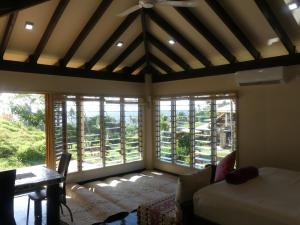 Cette chambre comprend un lit, une table et des fenêtres. dans l'établissement Fiji Lodge Vosa Ni Ua, à Savusavu