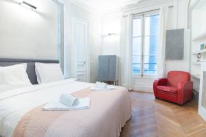 パリにあるDreamyflat - Champs Élyséesのベッドと赤い椅子が備わるホテルルームです。