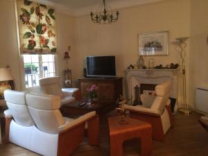 a living room with white chairs and a fireplace at Le Clos des Roys in Reims