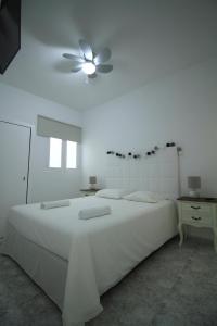 a white bedroom with a bed and a ceiling fan at COTILLO SEA in Cotillo