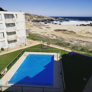 a swimming pool on the roof of a building next to the beach at Condominio borde mar las cruces in El Tabo