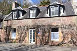 an old brick house with white doors and windows at 3 St Gilbert Street in Dornoch
