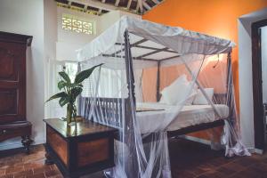 Dormitorio con cama con dosel y mesa con planta en Templeberg, en Galle