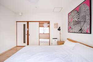 a bedroom with a white bed and a painting on the wall at Yuenshe Higashi Hongan-ji Villa in Kyoto