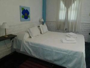 Una cama blanca con dos toallas en una habitación en Cabañas Los Girasoles en Gualeguaychú