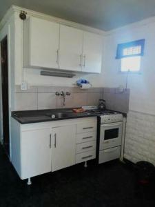 a kitchen with white cabinets and a sink and a stove at Cabañas Los Girasoles in Gualeguaychú