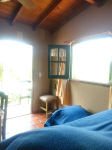 1 dormitorio con cama, ventana y silla en Zahra Depto en Villa Gesell