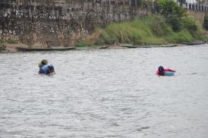 twee mensen in het water in een rivier bij Saksiri Riverside Boutique Hotel in Vang Vieng
