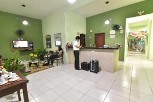 un hombre parado en un mostrador en una sala de espera en Pousada Paraíso dos Lençóis, en Barreirinhas