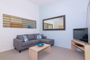 a living room with a couch and a flat screen tv at Angourie Resort in Yamba