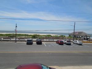 a parking lot with cars parked in front of the ocean at The Jetty Motel in Cape May