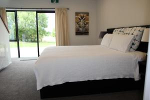 una camera da letto con un grande letto bianco e una finestra di Korepo Lodge @ Ruby Bay a Nelson