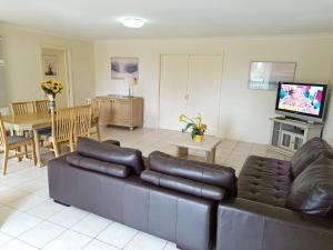 uma sala de estar com um sofá de couro e uma sala de jantar em Glen Inn em Glen Waverley