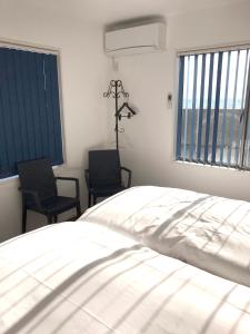 sypialnia z białym łóżkiem i 2 krzesłami w obiekcie UOGASHI 7070 Ocean View w mieście Naoshima