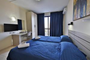 a hotel room with a blue bed and a desk at Relax Inn Hotel in St Paul's Bay