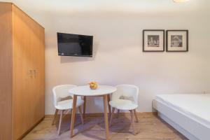 a room with a table and two chairs and a tv at Studios & Apartments Porto in Zadar