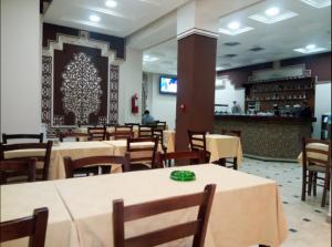 a restaurant with tables and chairs and a bar at Roza Hotel in Bab Ezzouar