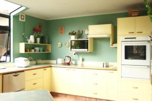 uma cozinha com armários brancos e uma parede verde em Hamilton East Homestay em Hamilton