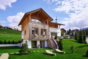 a house with a wooden roof on a green field at Villa Flora Mountain Lodges in San Cassiano