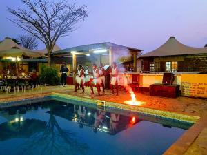 a group of people standing around a pool with a fire at Kampi Ya Boma Kolwezi in Kolwezi
