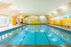 a large swimming pool with blue water in a building at Durbuy chalet 65 in Durbuy