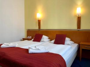 twee bedden in een hotelkamer met handdoeken erop bij Hotel Veritas in Boedapest