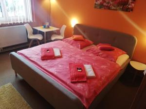 Un dormitorio con una cama con sábanas rosas y una mesa. en Pension Three, en Františkovy Lázně