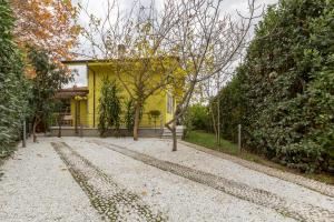 uma casa amarela com uma árvore no meio de uma estrada em Villa Twetty em Massaciuccoli
