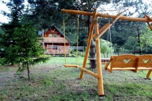 a wooden swing in a yard with a house at Sarzynówka in Krasnobród