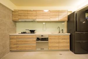 cocina con armarios de madera y nevera de acero inoxidable en Yilan Siao Jhu, en Jiaoxi