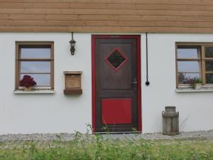 a red door on a white house with two windows at Holstein-Höfle - Gipfelstüble in Argenbühl