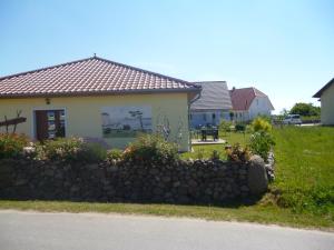 a house with a stone wall in front of a yard at Haus Wildrose in Dranske