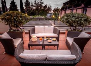 un patio con 2 sillas de mimbre y una mesa en BV Grand Hotel Assisi, en Asís