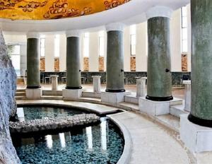 a building with a pool of water with columns at Amazing condo by the beach in Loutraki