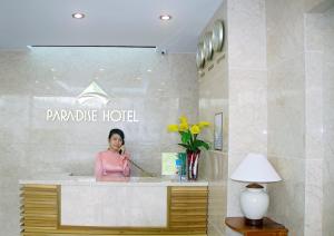 uma mulher a falar ao telemóvel na entrada de um hotel em Paradise Hotel em Da Nang