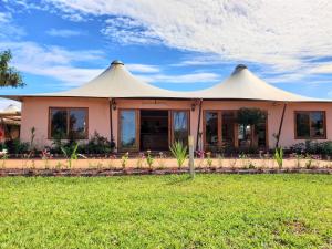 a house with a tent in the grass at Kampi Ya Boma Kolwezi in Kolwezi