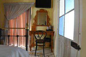 a bedroom with a bed and a chair and a mirror at Maria Giovanna Guest House in Marsalforn
