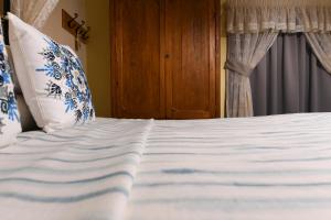 a bed with white sheets and blue and white pillows at Maria Giovanna Guest House in Marsalforn
